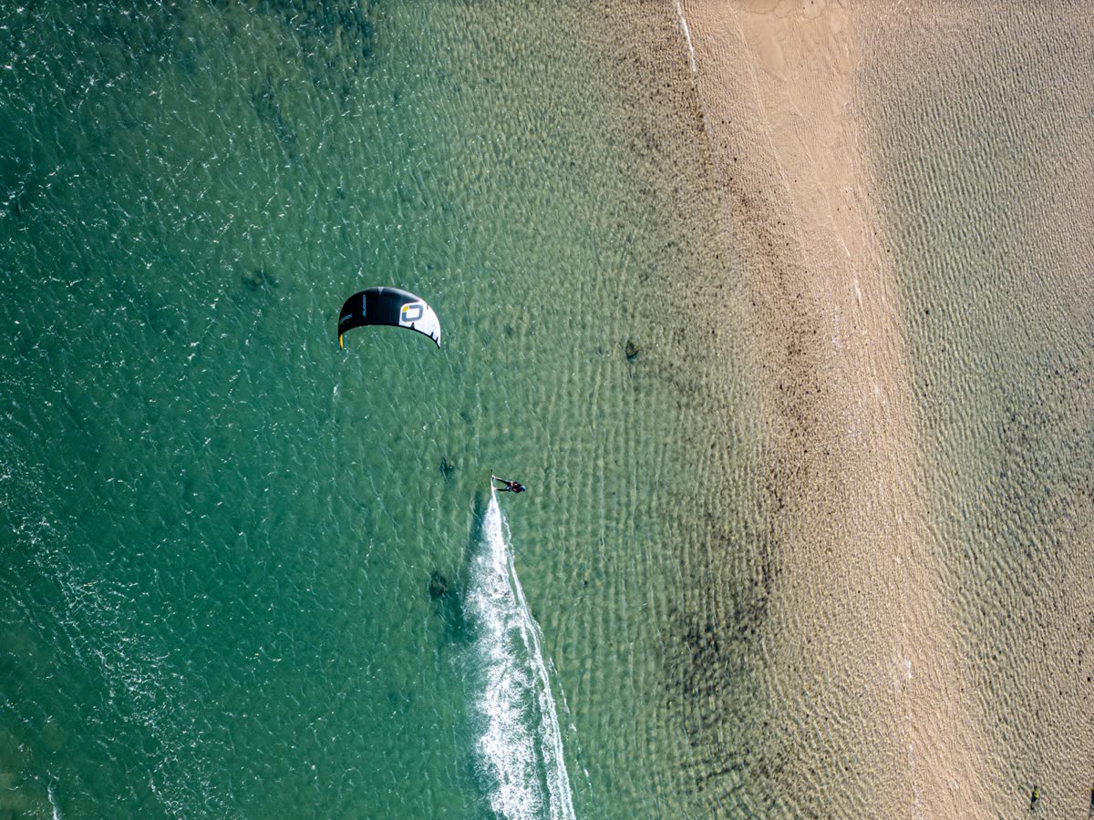 Vista aérea de un practicante de kitesurf trazando una estela en la Bahía de Cádiz