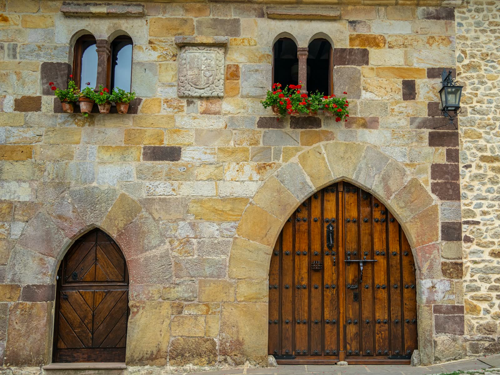 Fachada de piedra medieval con geranios rojos en Santillana del Mar