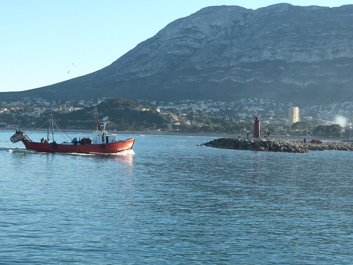 Barco pesquero entrando al puerto de Dénia con el macizo del Montgó al fondo