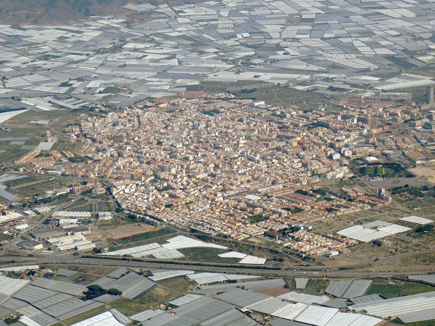 Vista aérea de El Ejido, con el núcleo urbano rodeado por el mar de invernaderos del poniente almeriense
