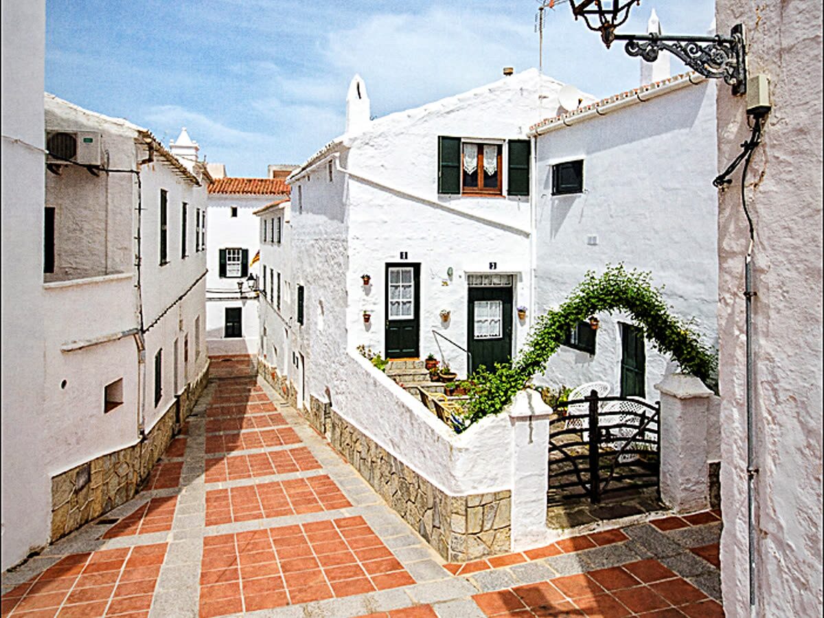 Calle empedrada entre casas encaladas del casco tradicional de Es Mercadal, Menorca