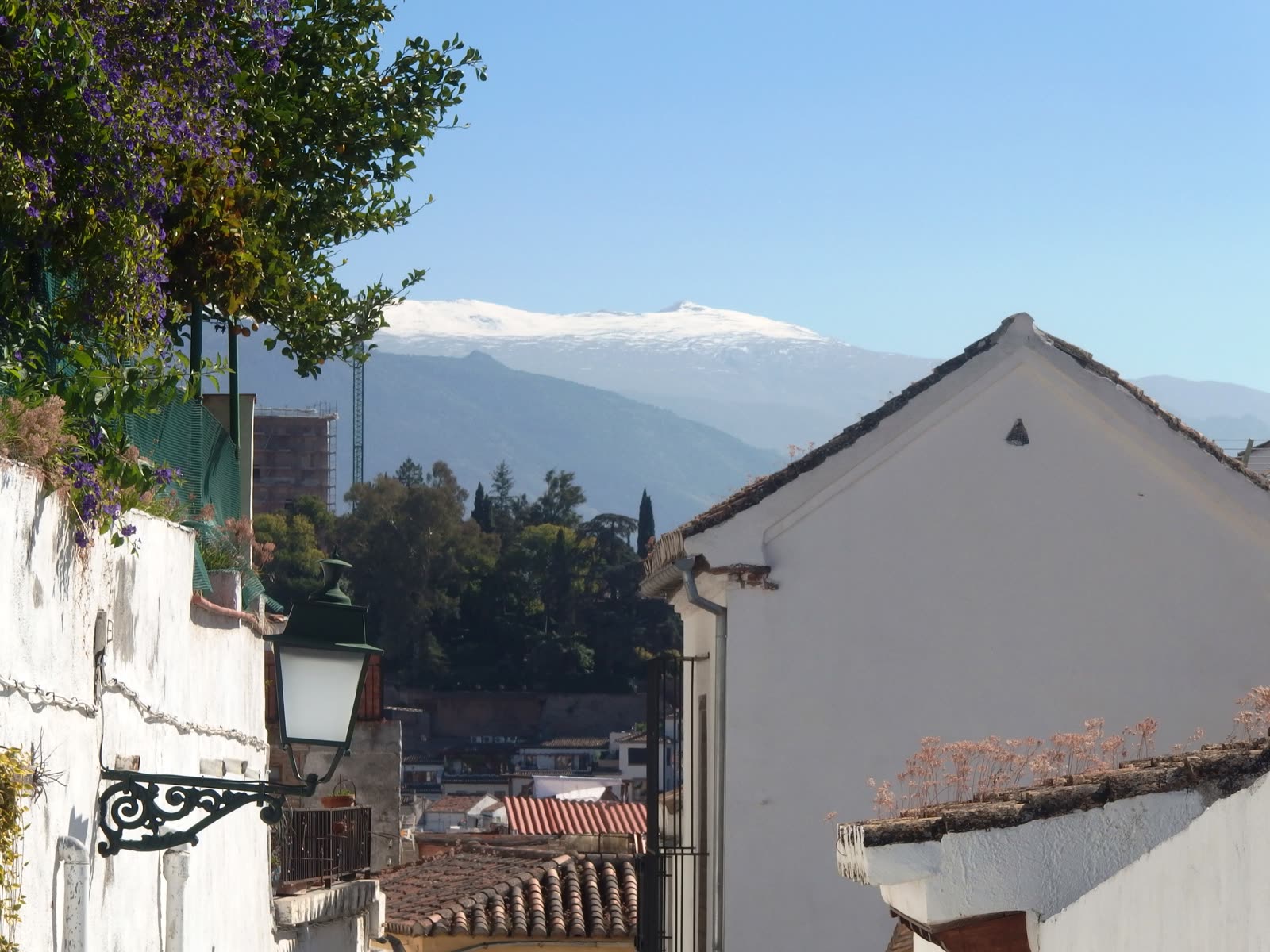 Sierra Nevada nevada al fondo, vista desde una calle del Albaicín en Granada