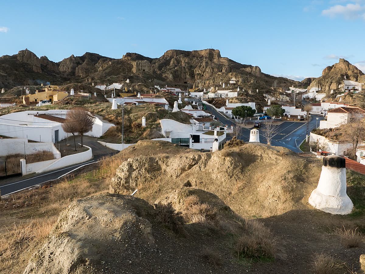 Casas cueva encaladas con chimeneas blancas sobre el paisaje de badlands de Guadix