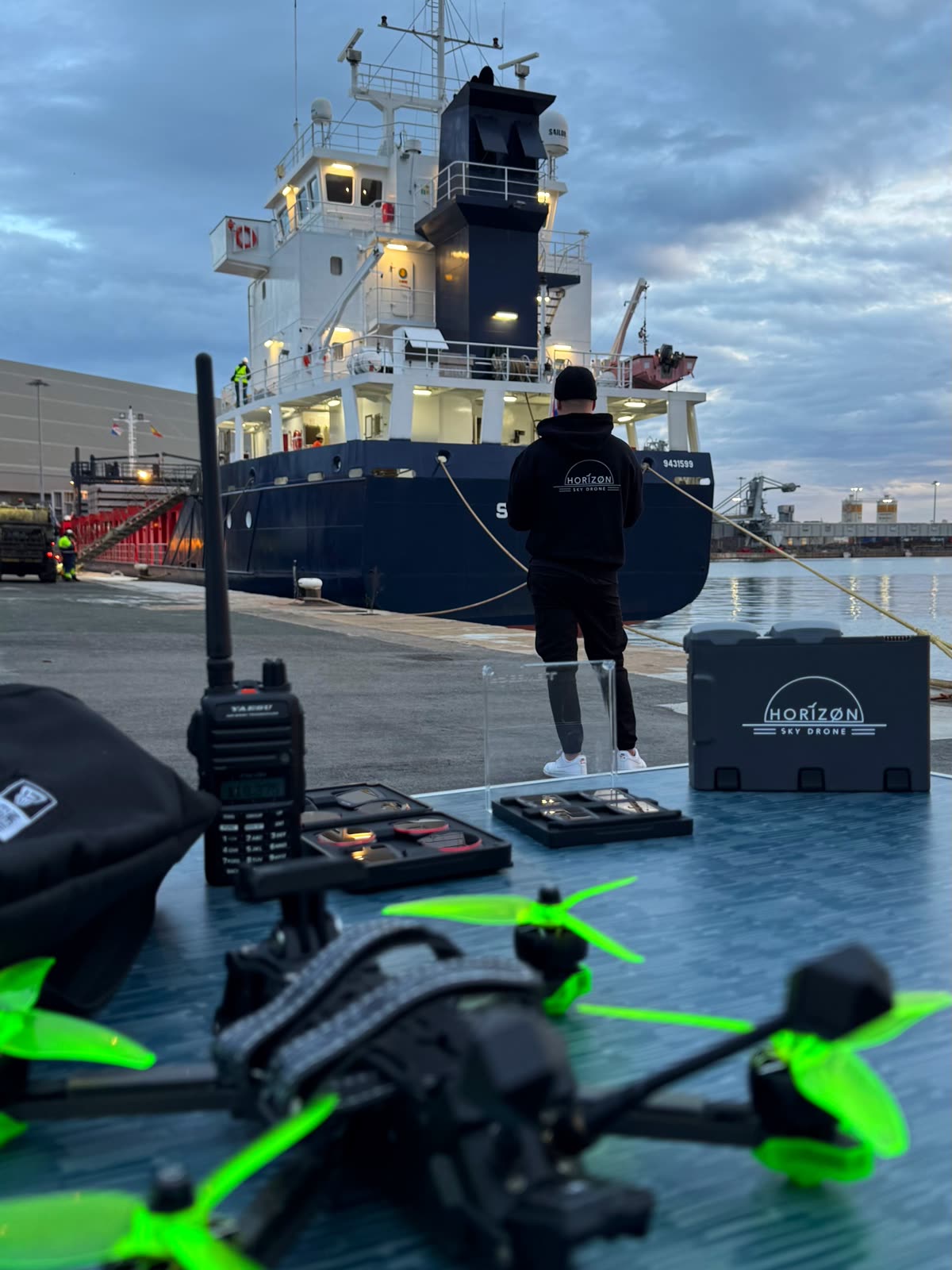 Piloto de Horizon Sky Drone con radio y gafas FPV junto a un buque en puerto