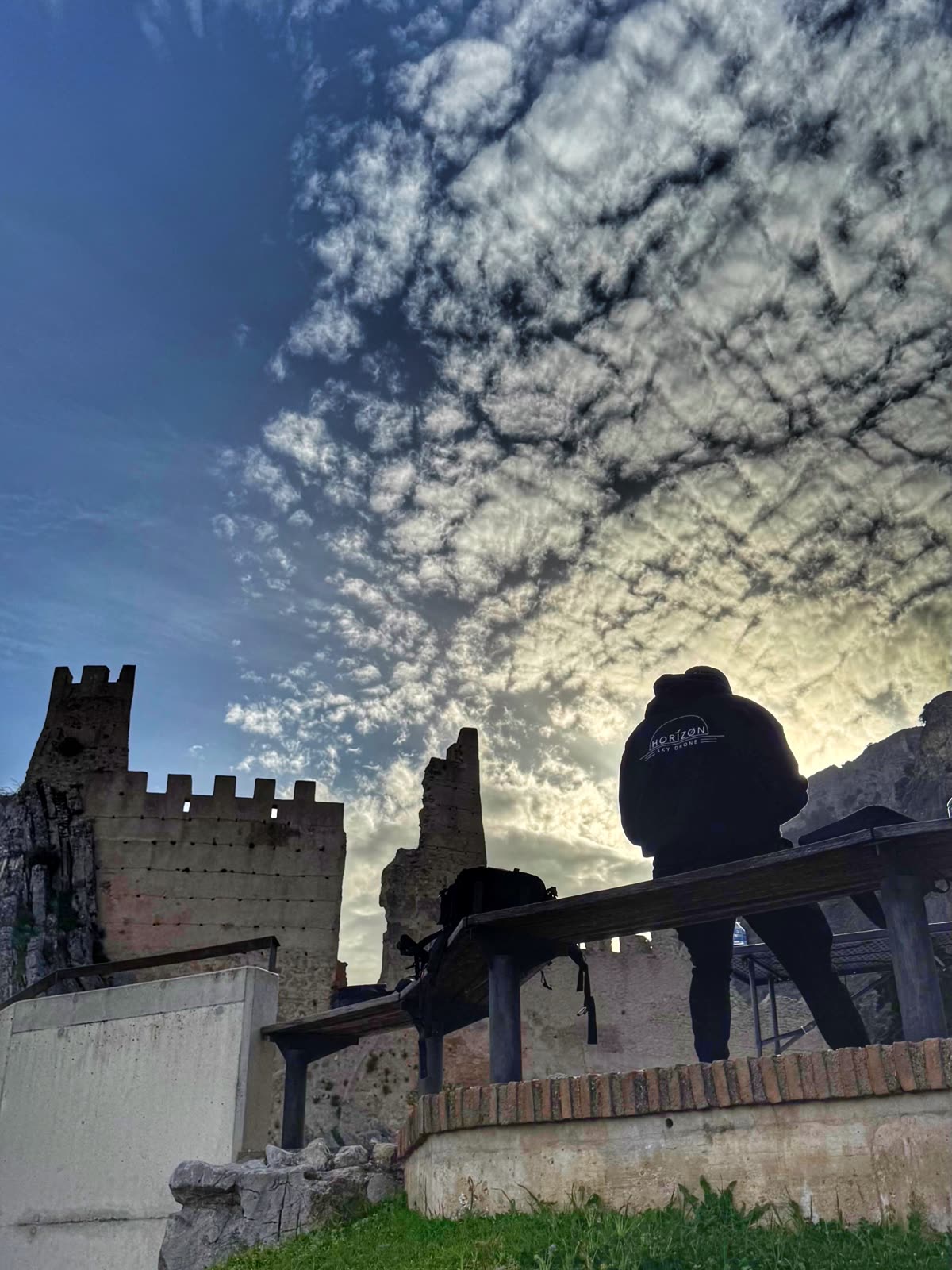 Silueta de un piloto de Horizon Sky Drone junto a las almenas de un castillo al atardecer