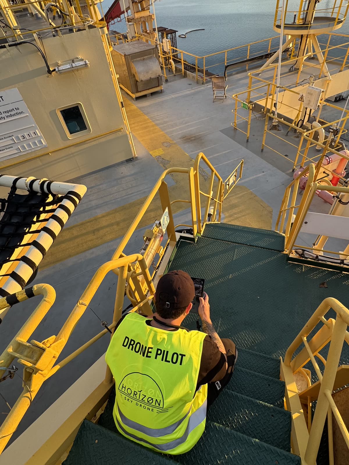Piloto de Horizon Sky Drone con una tablet en las escaleras de un buque, vista elevada del puerto