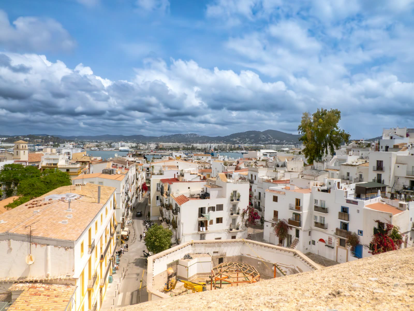 Vista elevada del casco antiguo de Ibiza con casas blancas y el puerto al fondo