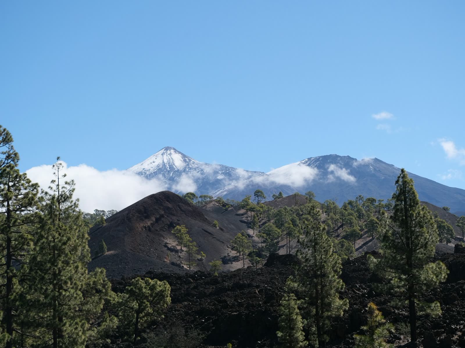 El Teide nevado asomando entre nubes sobre el paisaje volcánico de Tenerife