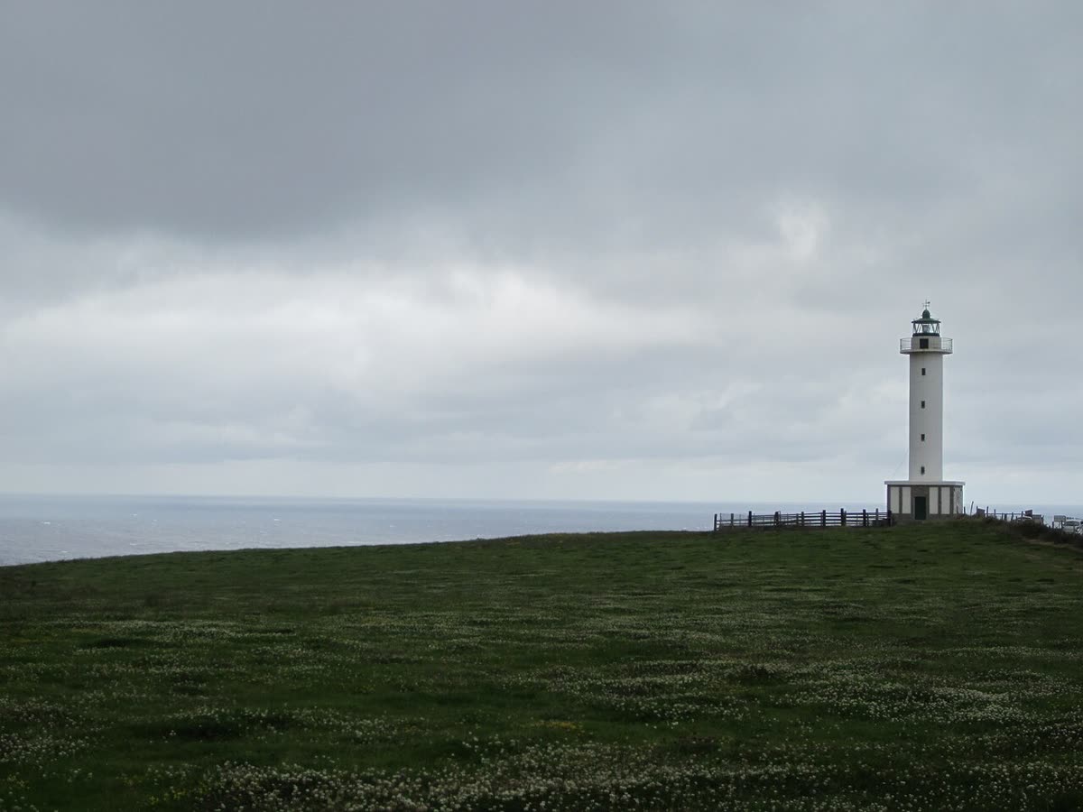 Faro de Lastres sobre un acantilado verde frente al mar Cantábrico