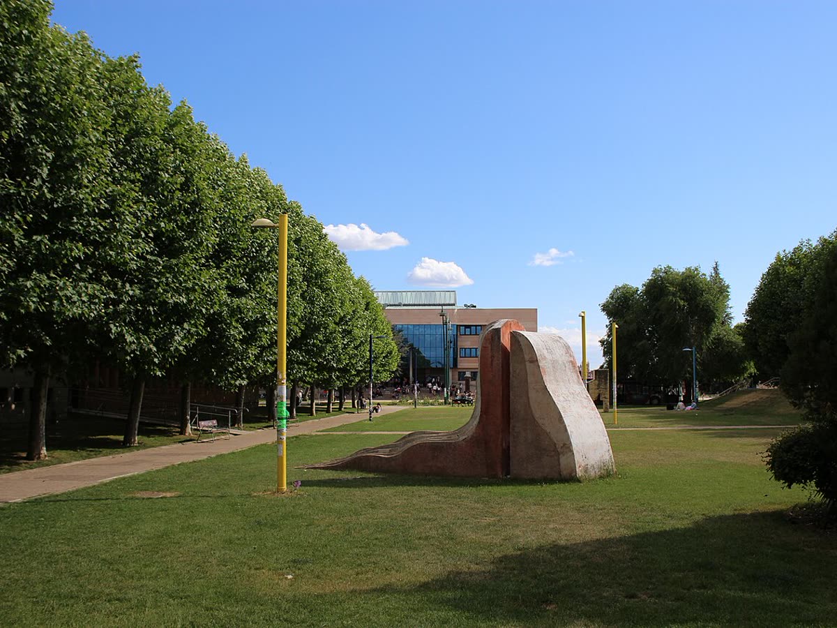 Zona ajardinada del campus de Vegazana de la Universidad de León con edificio de fondo