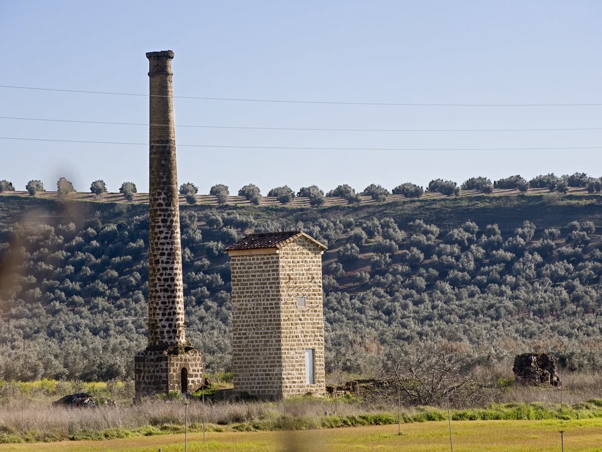 Chimenea y castillete de una antigua mina de plomo del siglo XIX en el paisaje minero de Linares