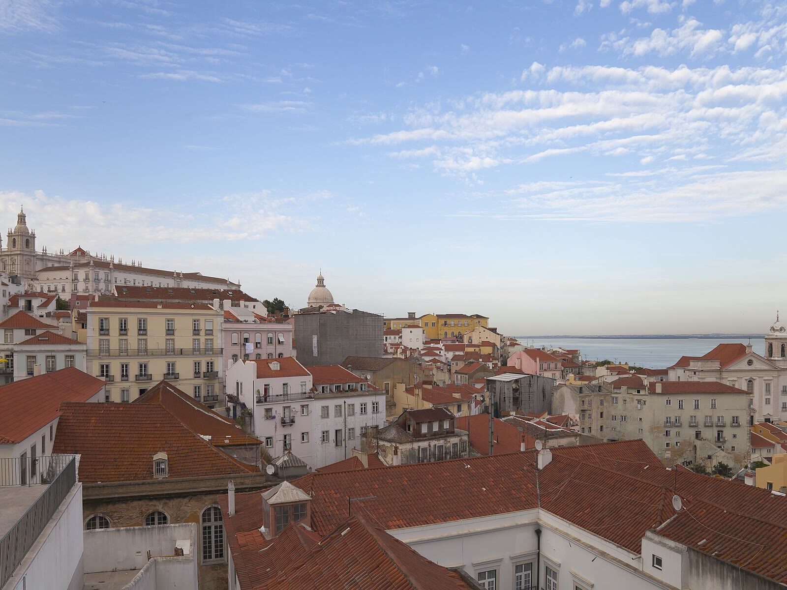 Vista elevada de los tejados de Alfama en Lisboa con el estuario del Tajo al fondo
