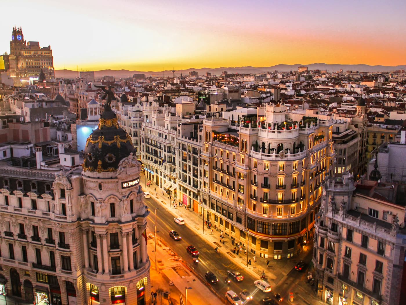 Vista aérea de la Gran Vía de Madrid al atardecer, con el edificio Metrópolis en primer término