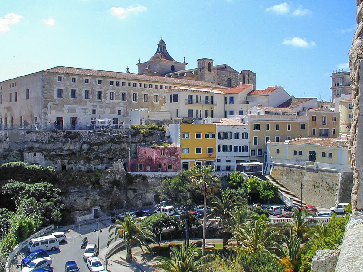 Casco histórico de Mahón, con fachadas de colores y la iglesia del Carme sobre la muralla del puerto