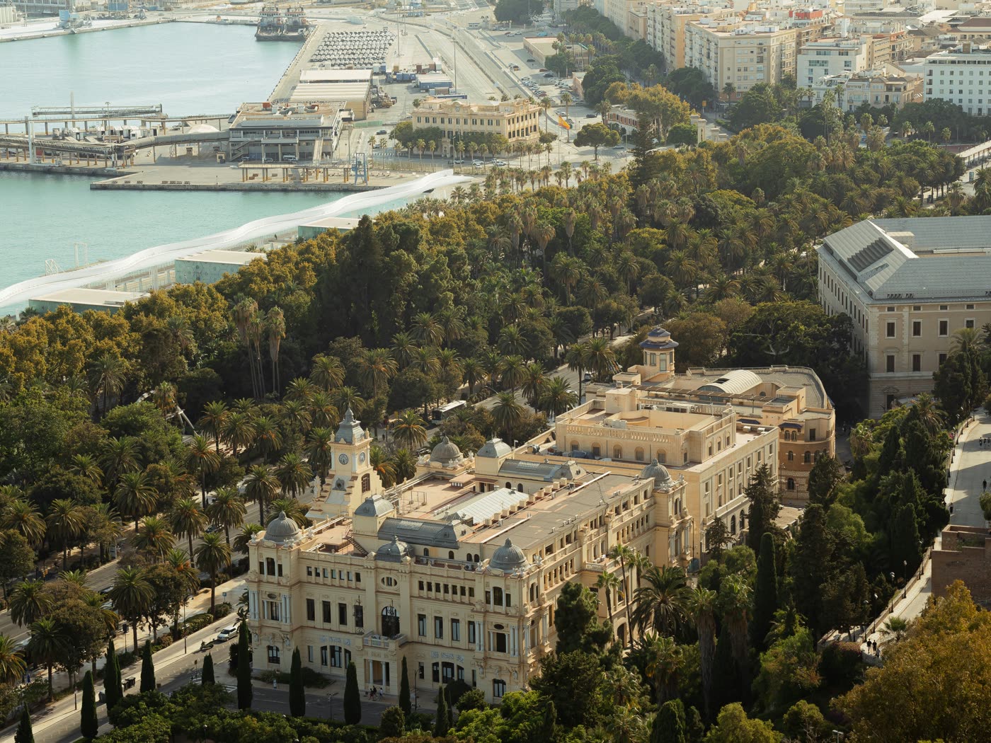 Vista aérea del Ayuntamiento de Málaga junto al Parque y el puerto, con la sierra al fondo