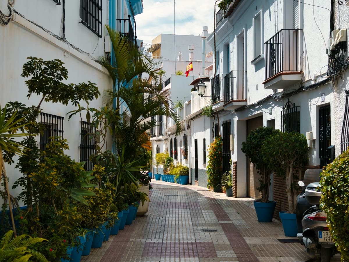 Calle estrecha del casco antiguo de Marbella con fachadas blancas y macetas