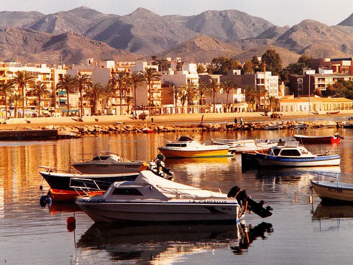 Embarcaciones amarradas en el puerto de Mazarrón con el pueblo y las montañas al fondo
