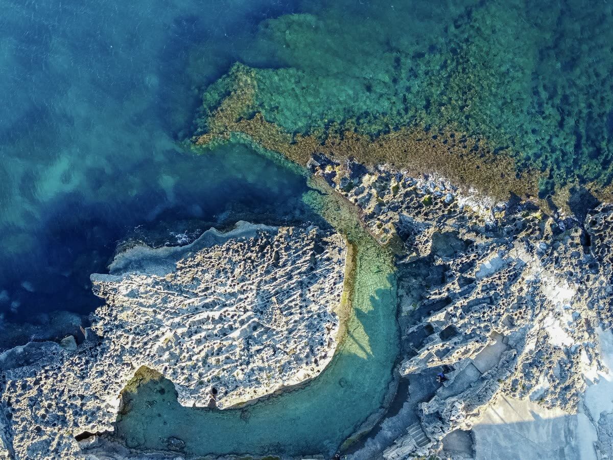 Vista aérea de una costa rocosa con aguas turquesas transparentes