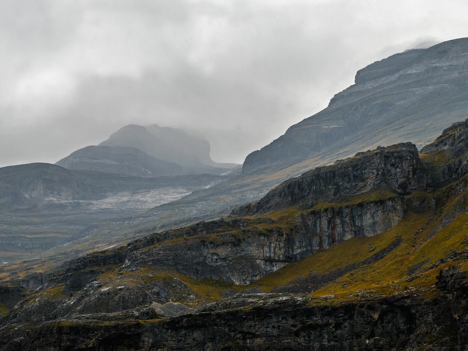 Macizo de Monte Perdido entre nubes bajas, con laderas de tonos ocres en otoño
