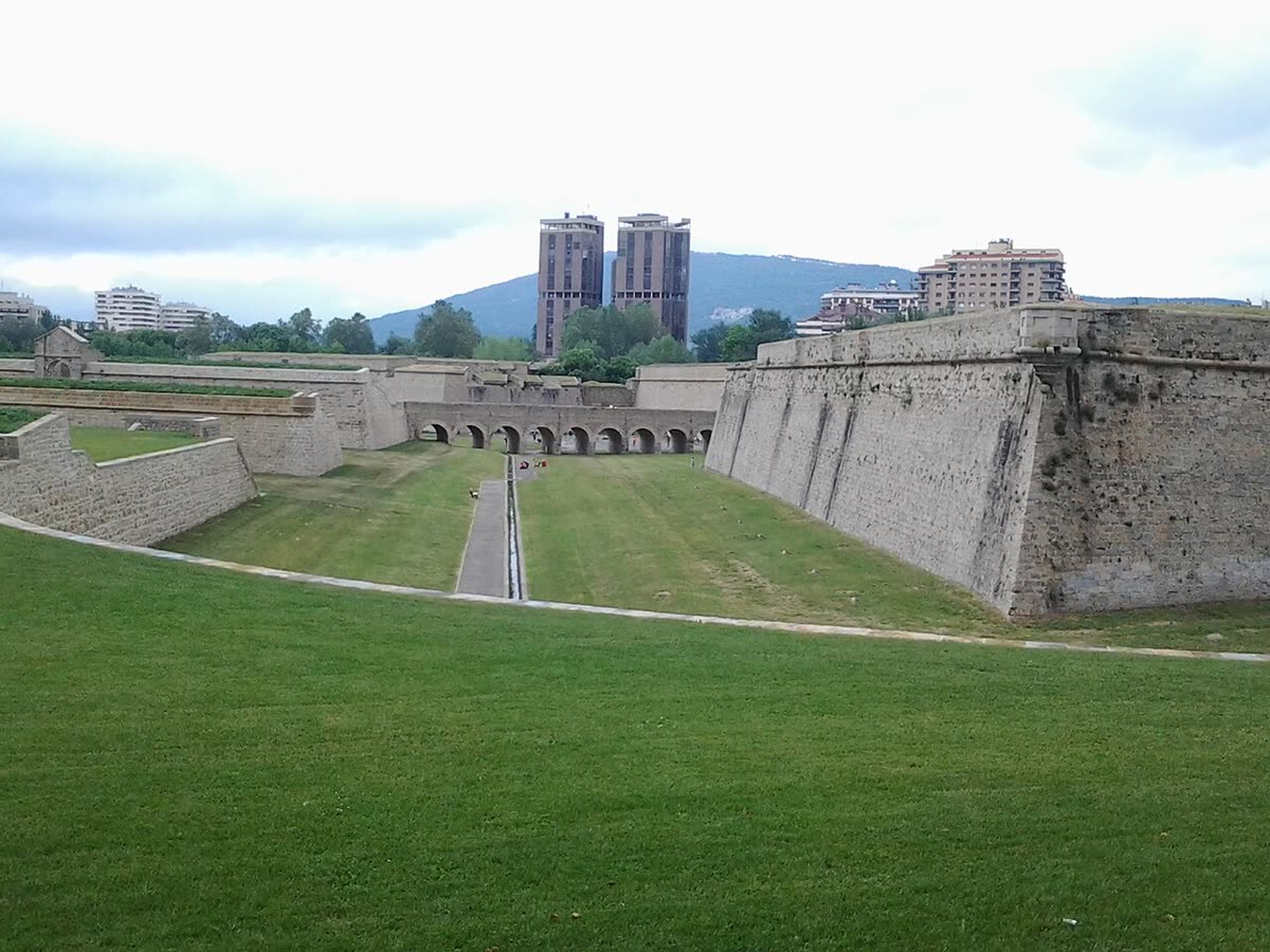 Foso y baluartes de piedra de la Ciudadela de Pamplona, con la ciudad al fondo
