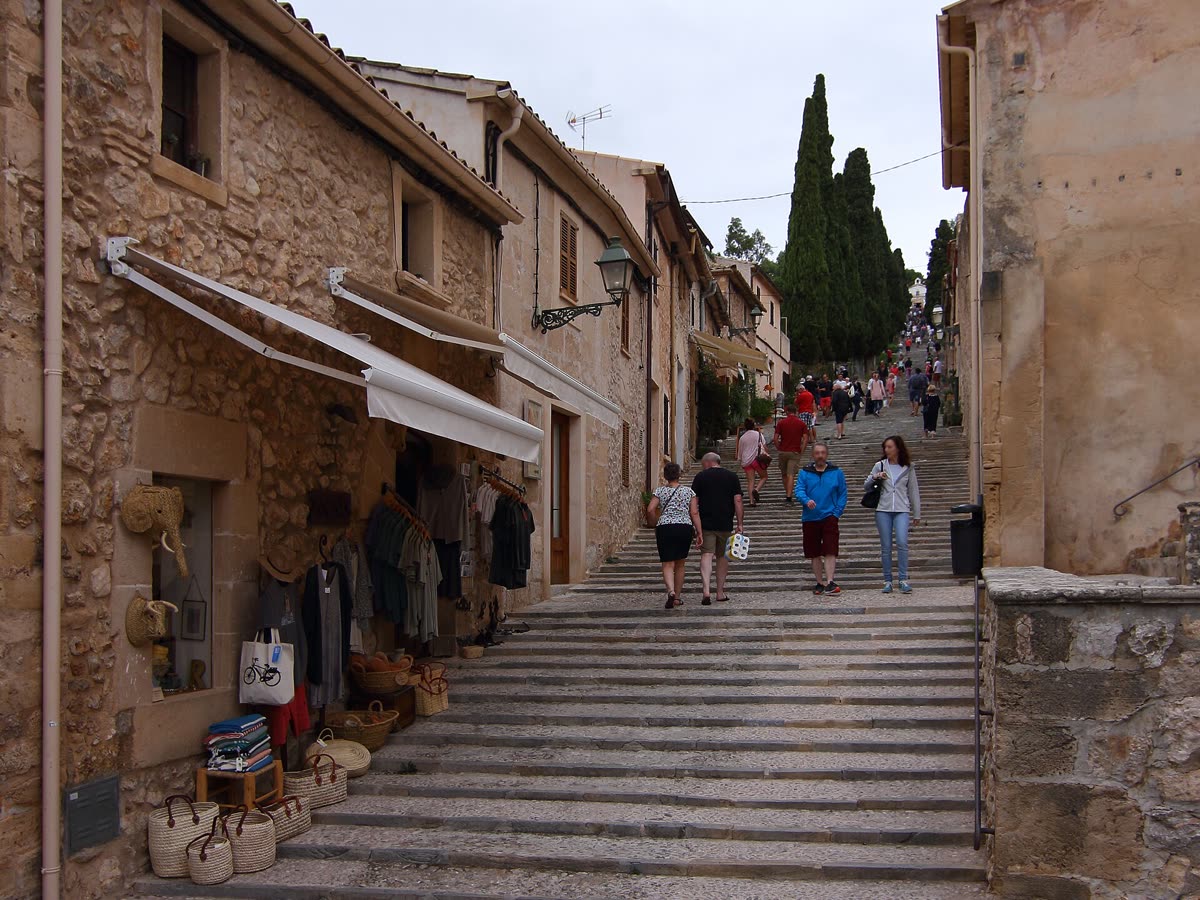 Escalinata del Calvari de Pollença, flanqueada por casas de piedra y cipreses