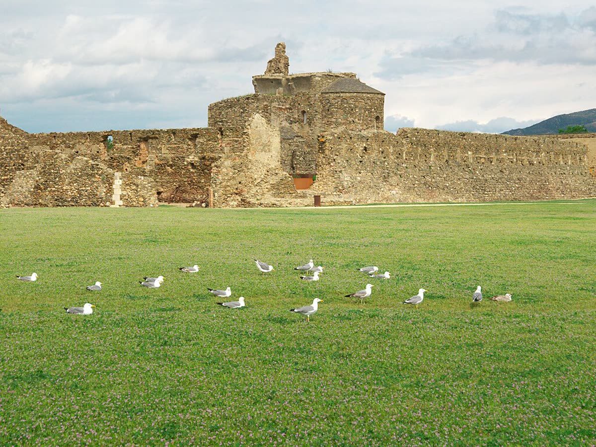 Muralla de piedra y restos históricos superpuestos de la Ciutadella de Roses