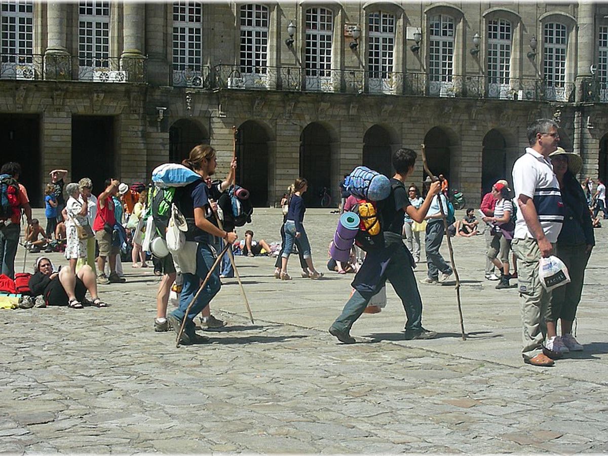 Peregrinos con mochilas llegando a la Praza do Obradoiro en Santiago de Compostela