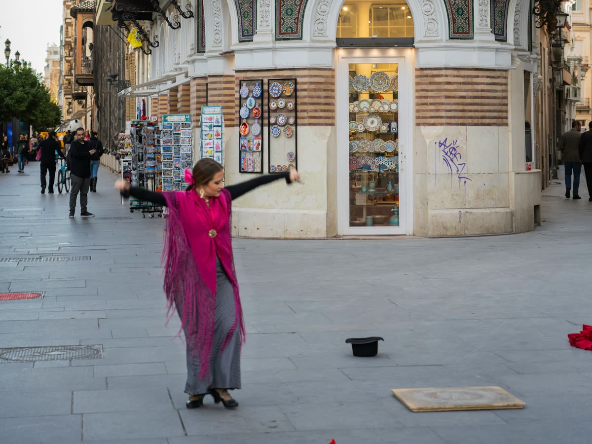 Bailaora de flamenco con mantón rosa bailando en una calle del centro de Sevilla