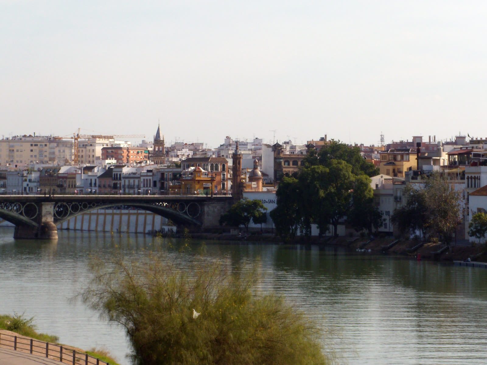Vista del Guadalquivir hacia Triana en Sevilla, con el Puente de Isabel II y la torre de la Capilla del Carmen