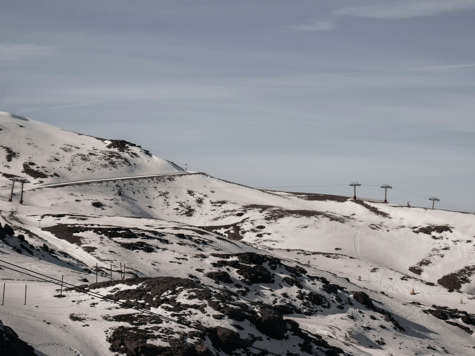 Pistas de esquí y telesilla en la estación de Sierra Nevada con la sierra nevada al fondo