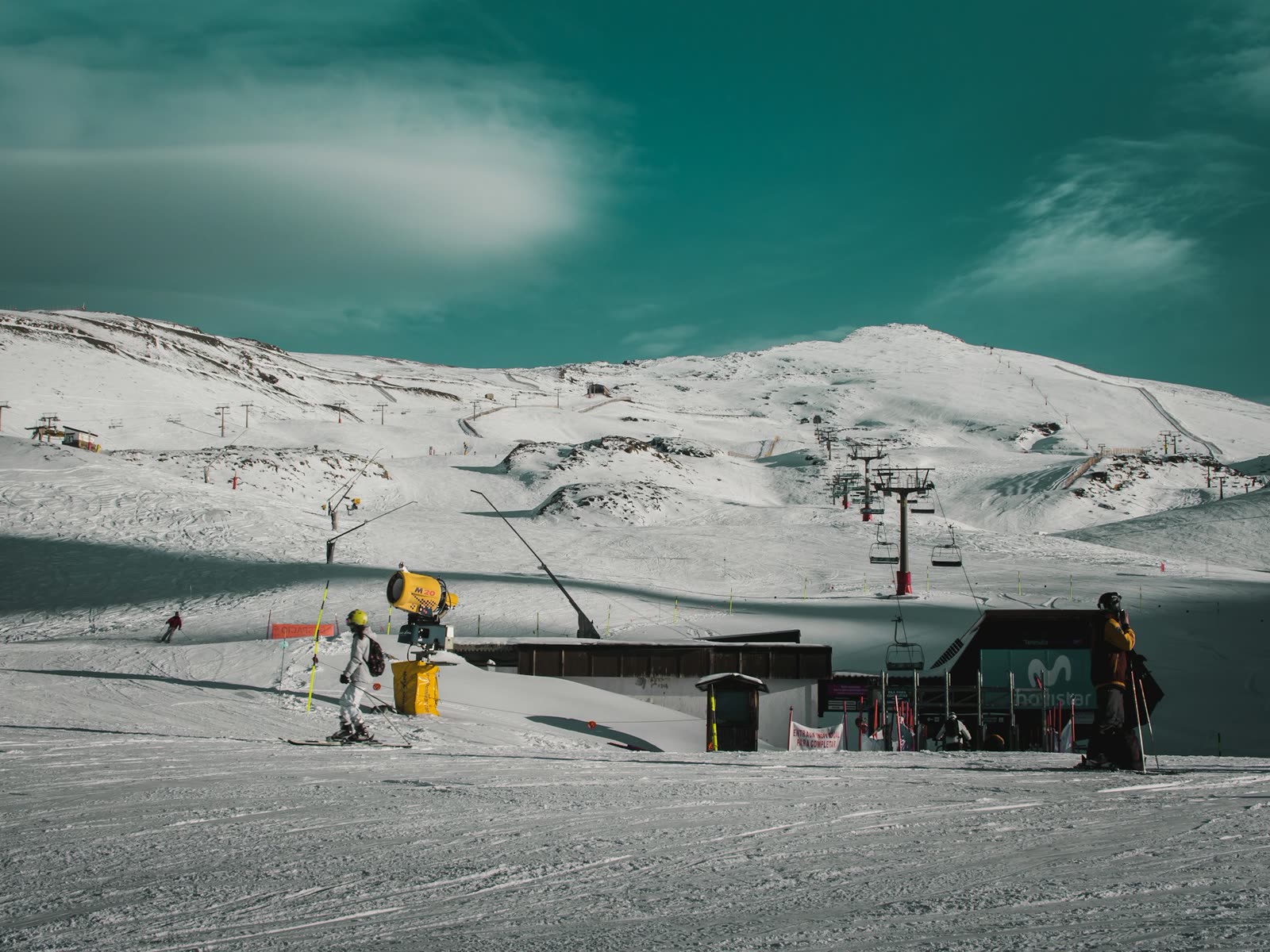 Esquiador y remonte en la estación de Pradollano, Sierra Nevada, con la montaña nevada al fondo