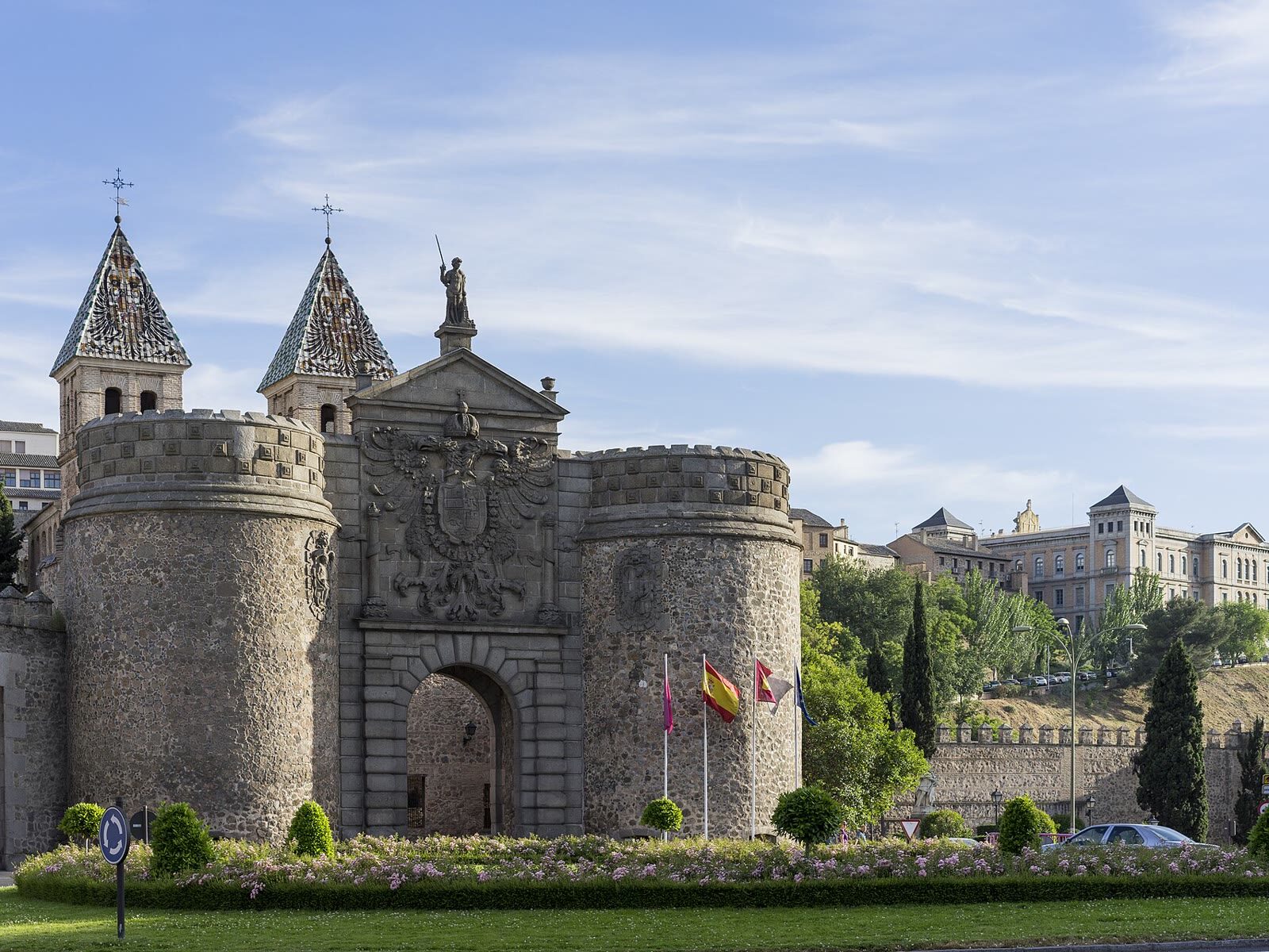Puerta de Bisagra de Toledo con sus torreones y chapiteles de cerámica bajo un cielo azul