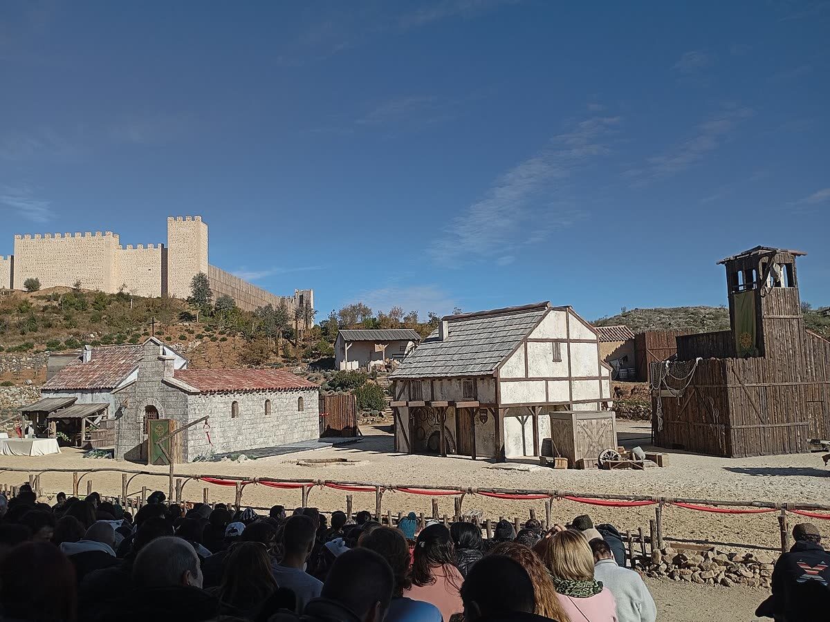Público asistiendo a una recreación histórica en el parque Puy du Fou España, en Toledo, con la muralla al fondo