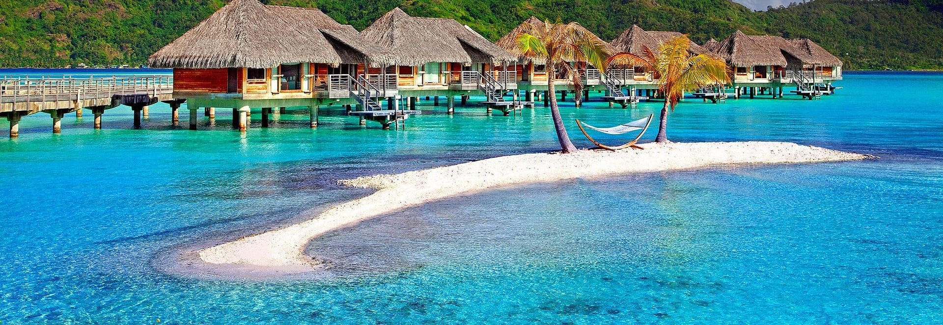 Bungalows sobre el agua de un resort tropical, junto a una playa de arena blanca