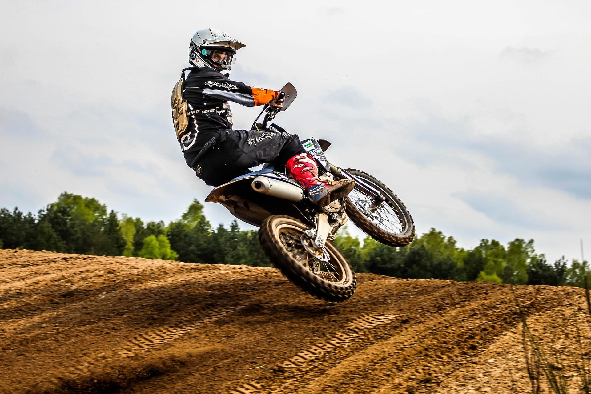 Piloto de motocross en pleno salto sobre un circuito de tierra