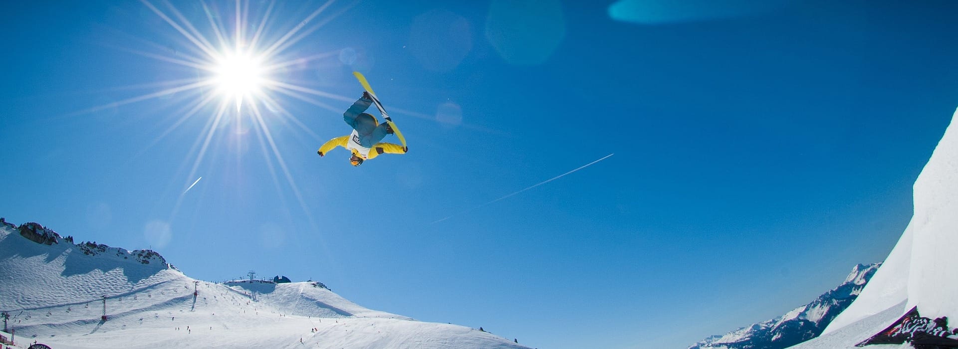 Snowboarder haciendo un salto invertido sobre una pista de alta montaña