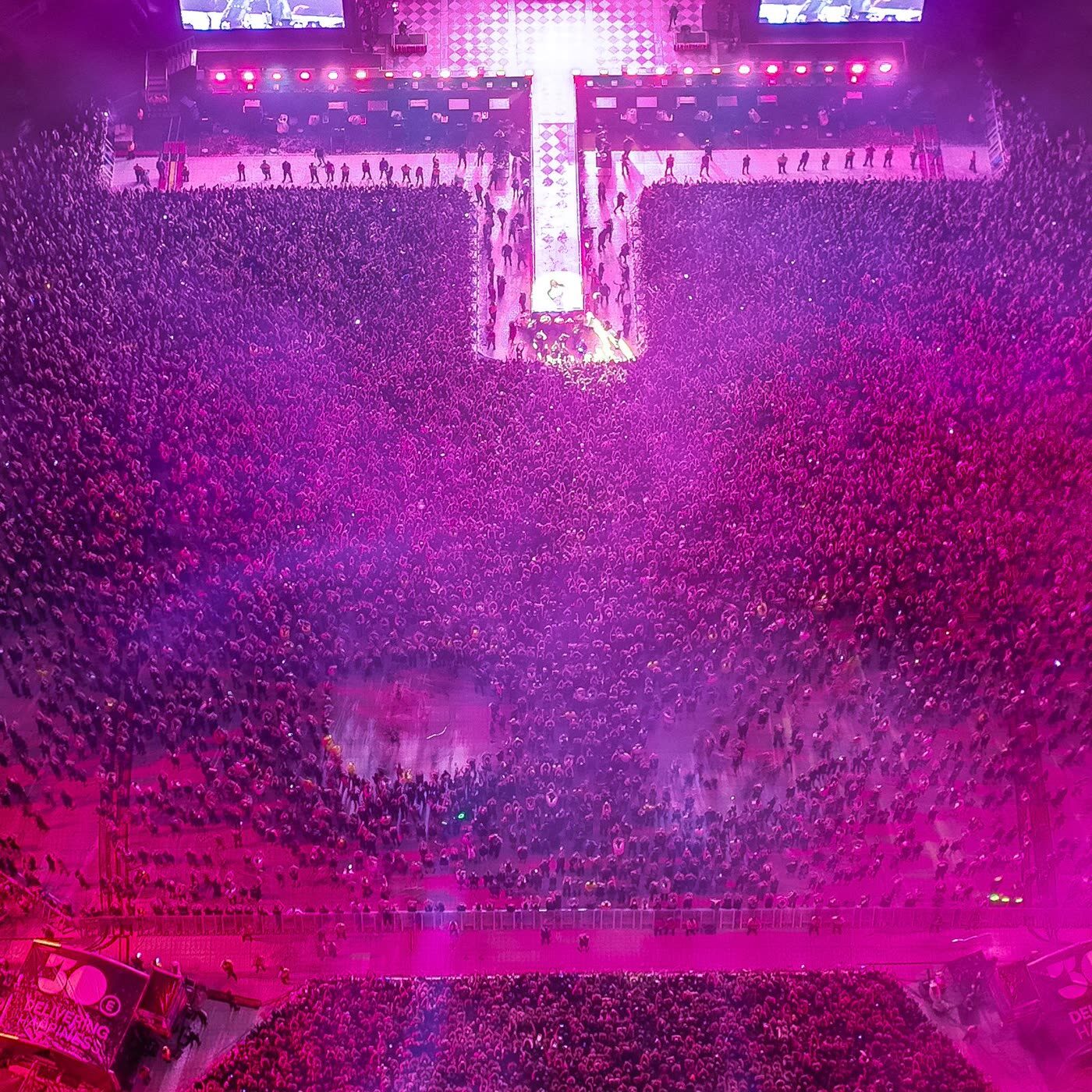 Vista aérea de un concierto multitudinario en un estadio con iluminación de escenario