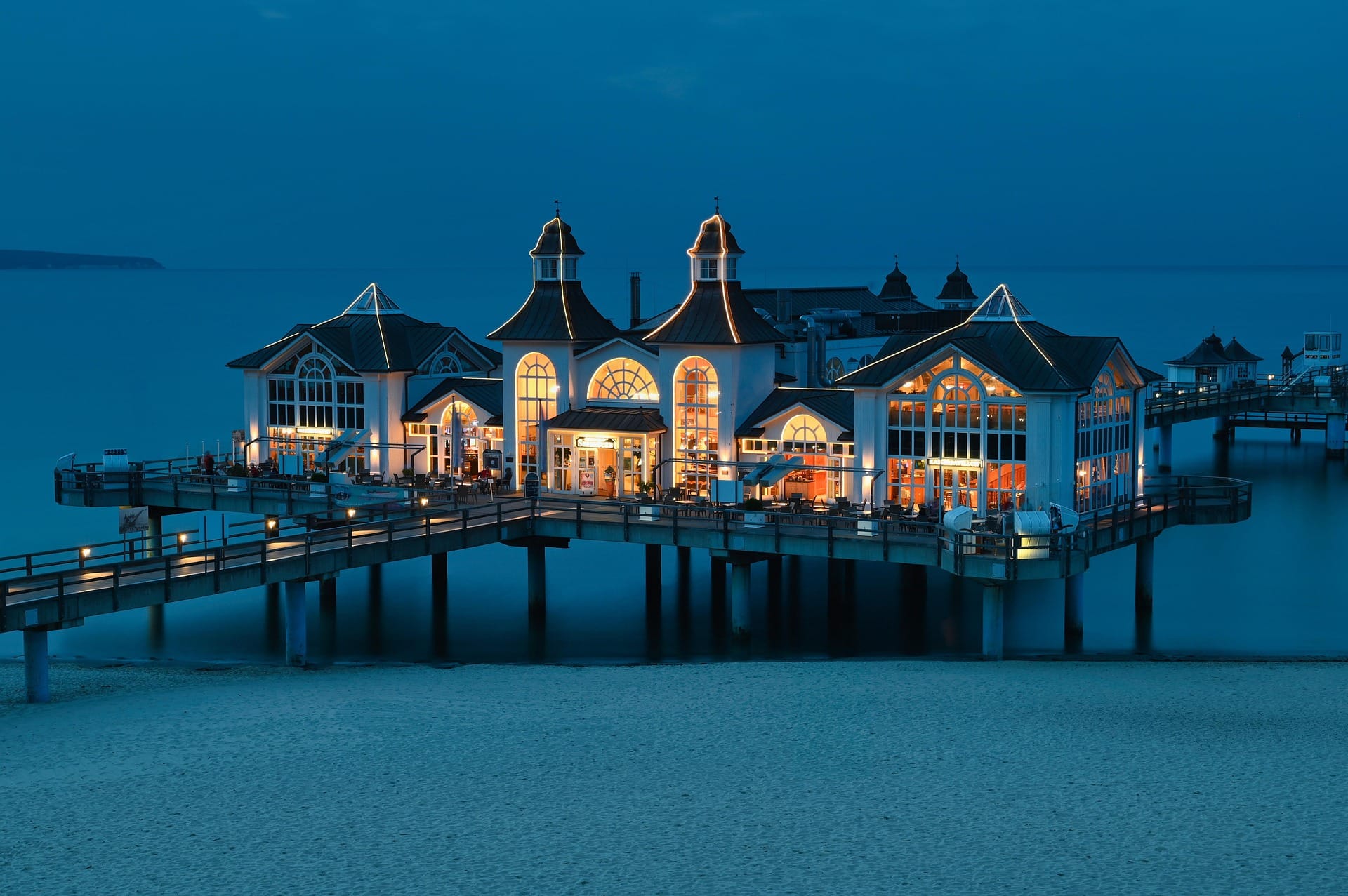 Restaurante iluminado sobre un muelle frente al mar al anochecer