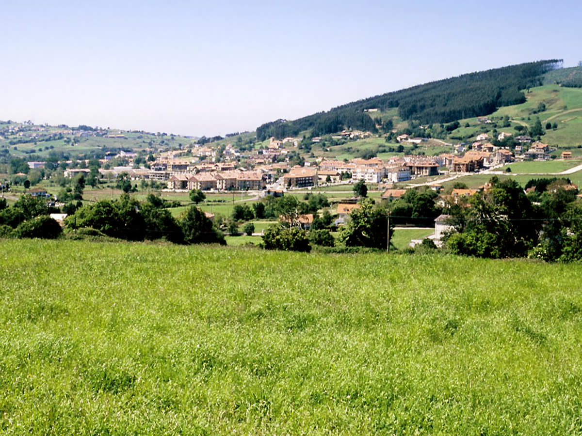 Prados verdes y caserío de Meruelo asomando entre colinas, en la Cantabria rural