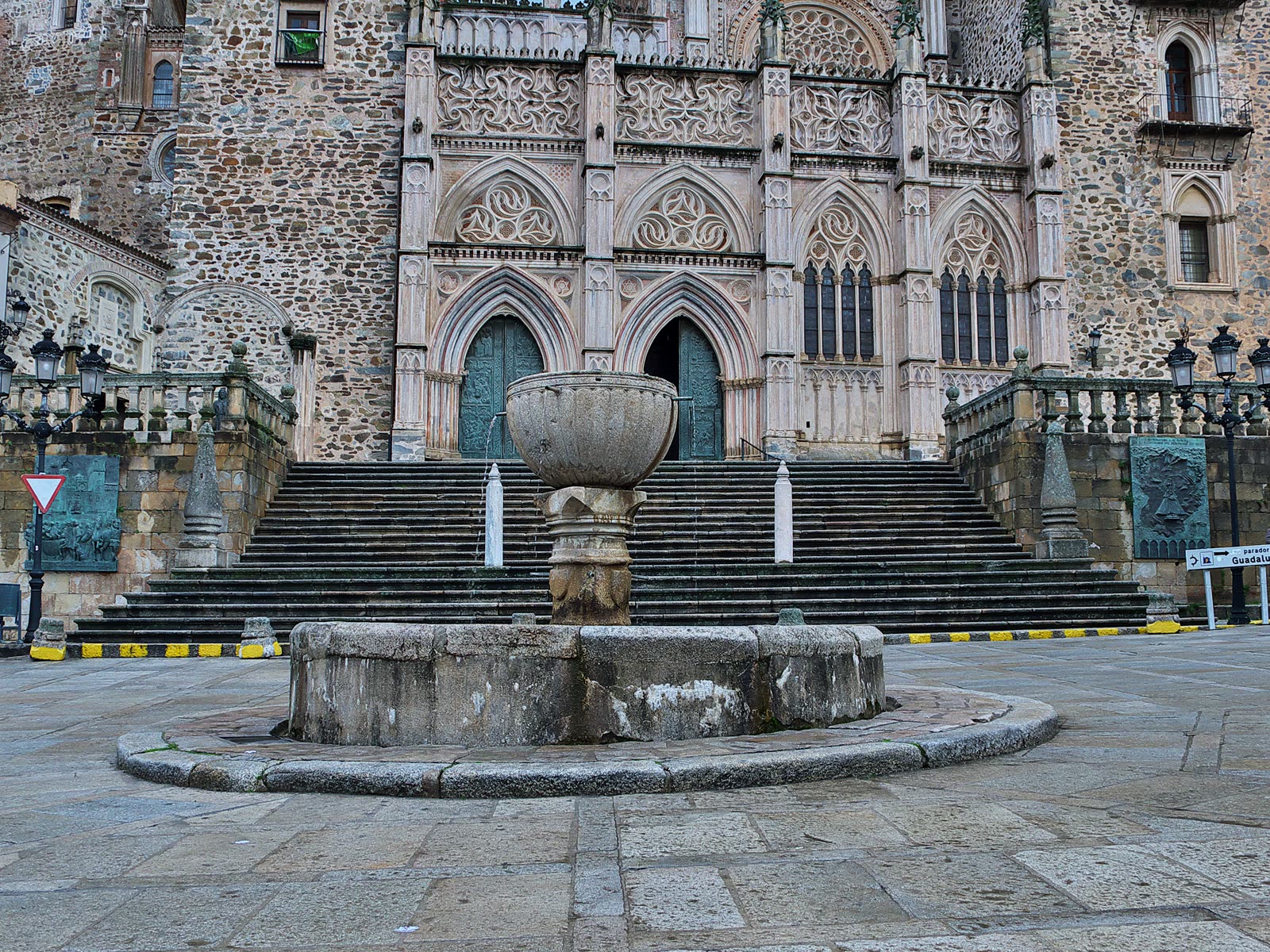 Fachada gótico-mudéjar del Real Monasterio de Santa María de Guadalupe, con la fuente de la plaza en primer término