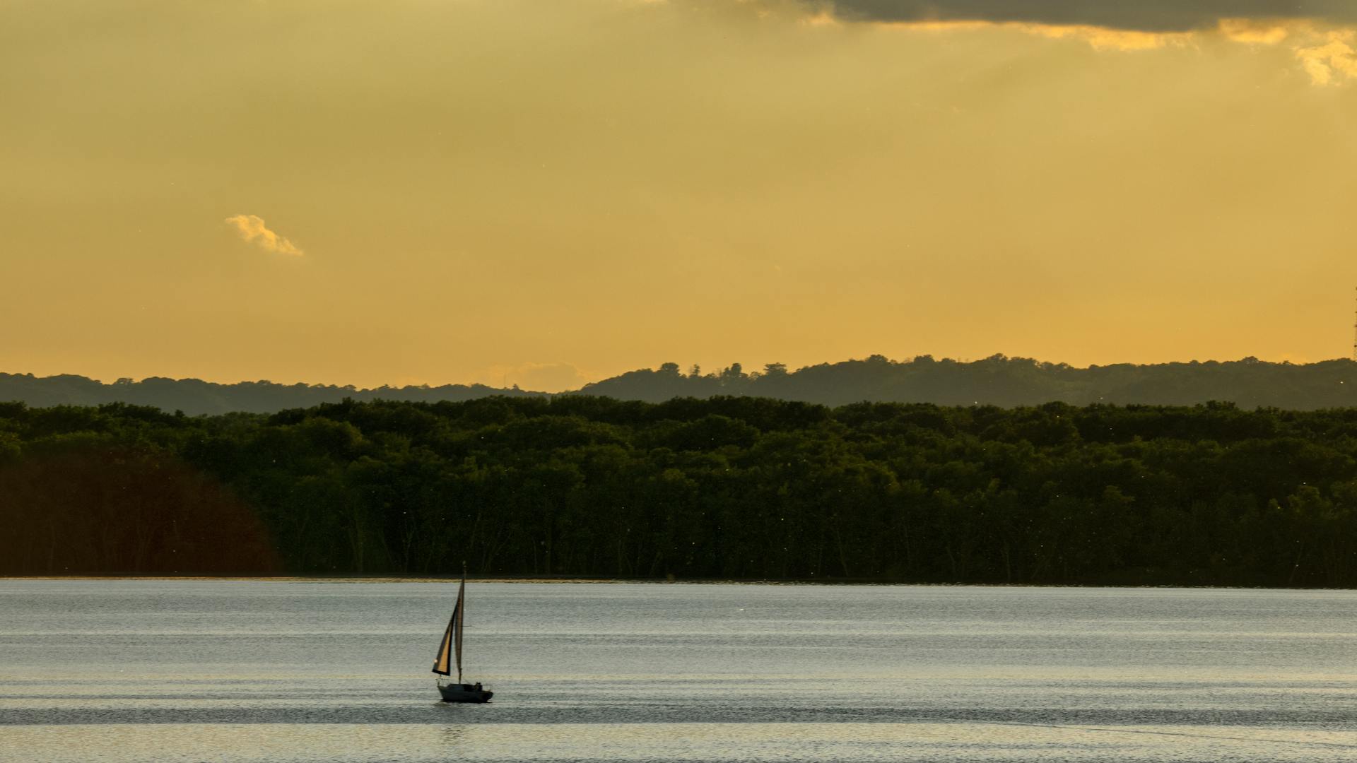 Segelboot auf einem ruhigen See im goldenen Sonnenuntergang – Segeln in Berlin mit Quipleon