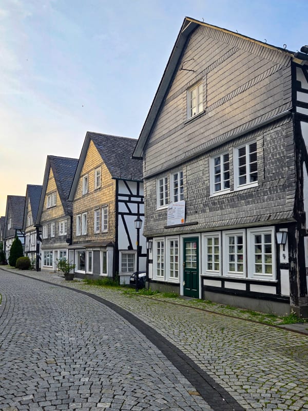 Half-timbered buildings and cobblestone street with a sunset reflection