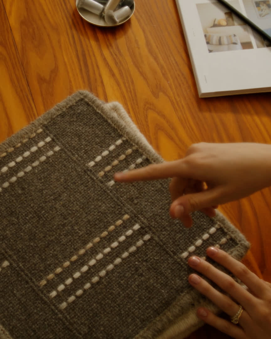 A hand points to a rug