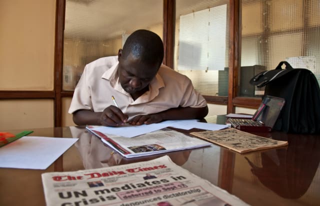 Kunyenje drawing at his desk.