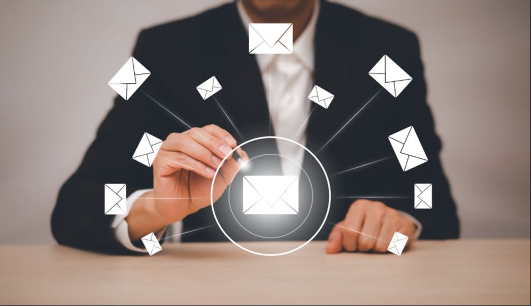 A person in a business suit tapping a glowing email icon surrounded by digital envelopes, representing email communication or marketing.