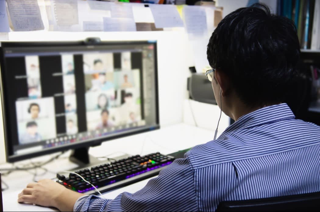Person attending a virtual meeting on a large computer screen with multiple participants visible, suggesting a remote work environment.