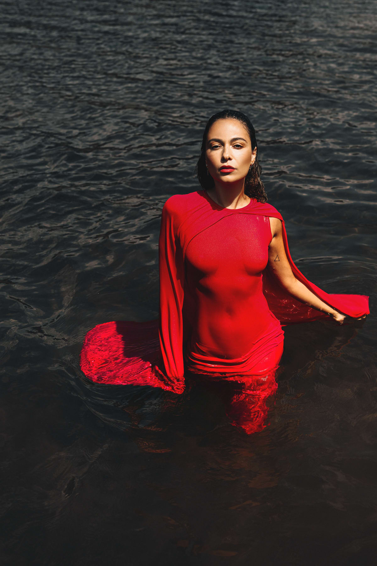 Model in rode jurk in het water, editorial shoot
