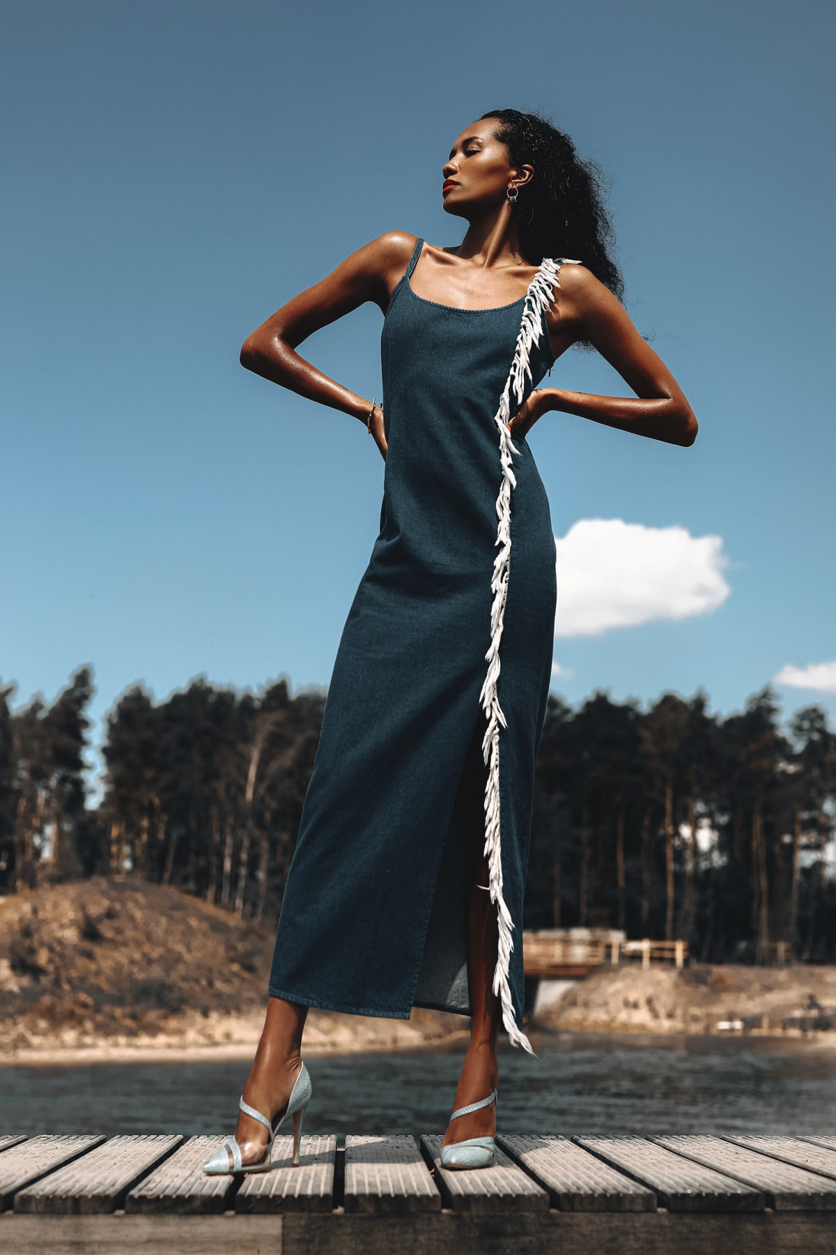 Model in denim jurk met witte franjes op een steiger, editorial shoot