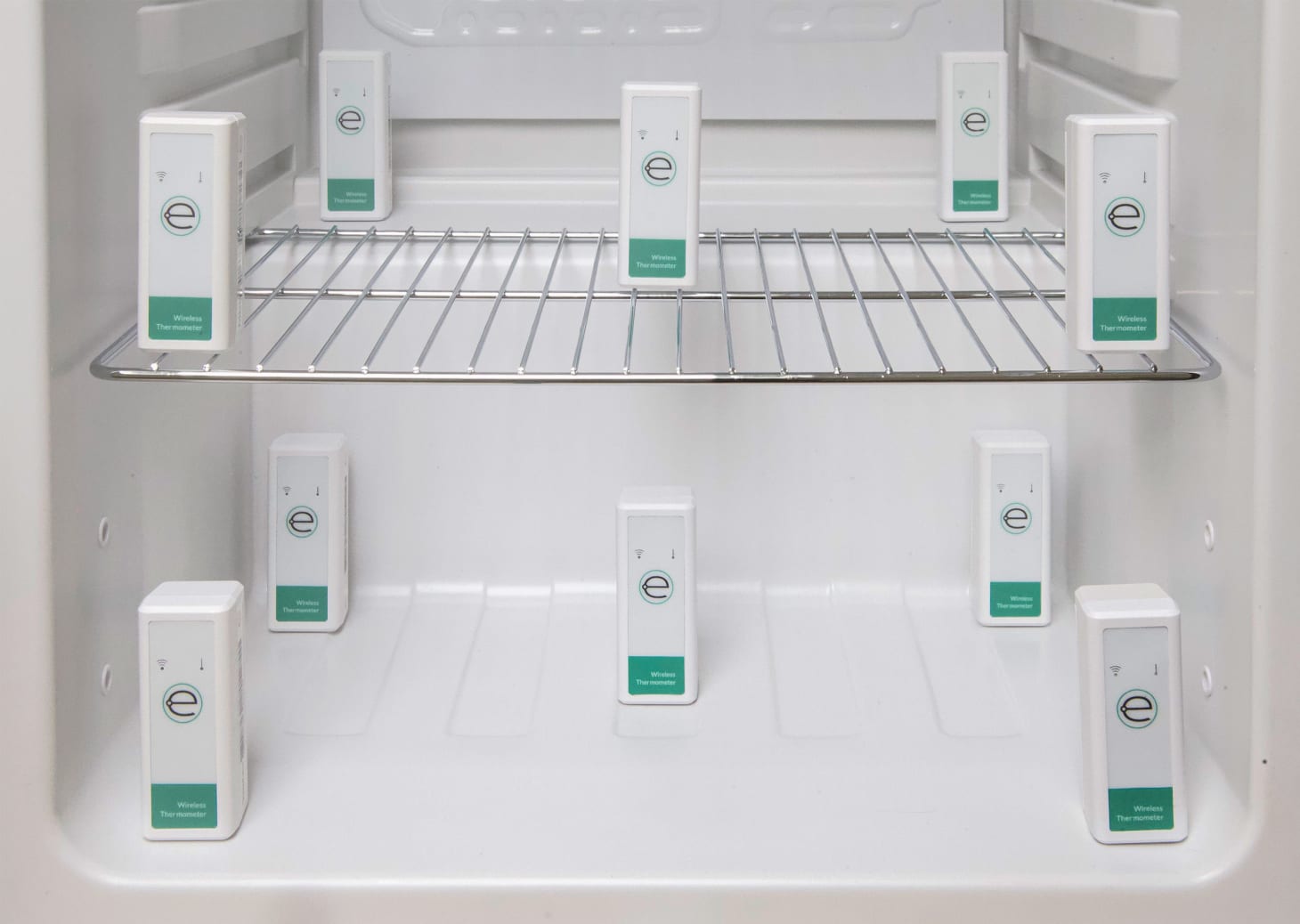 Interior of an empty refrigerator with 10 Eupry wireless thermometer sensors placed on two shelves for temperature mapping.