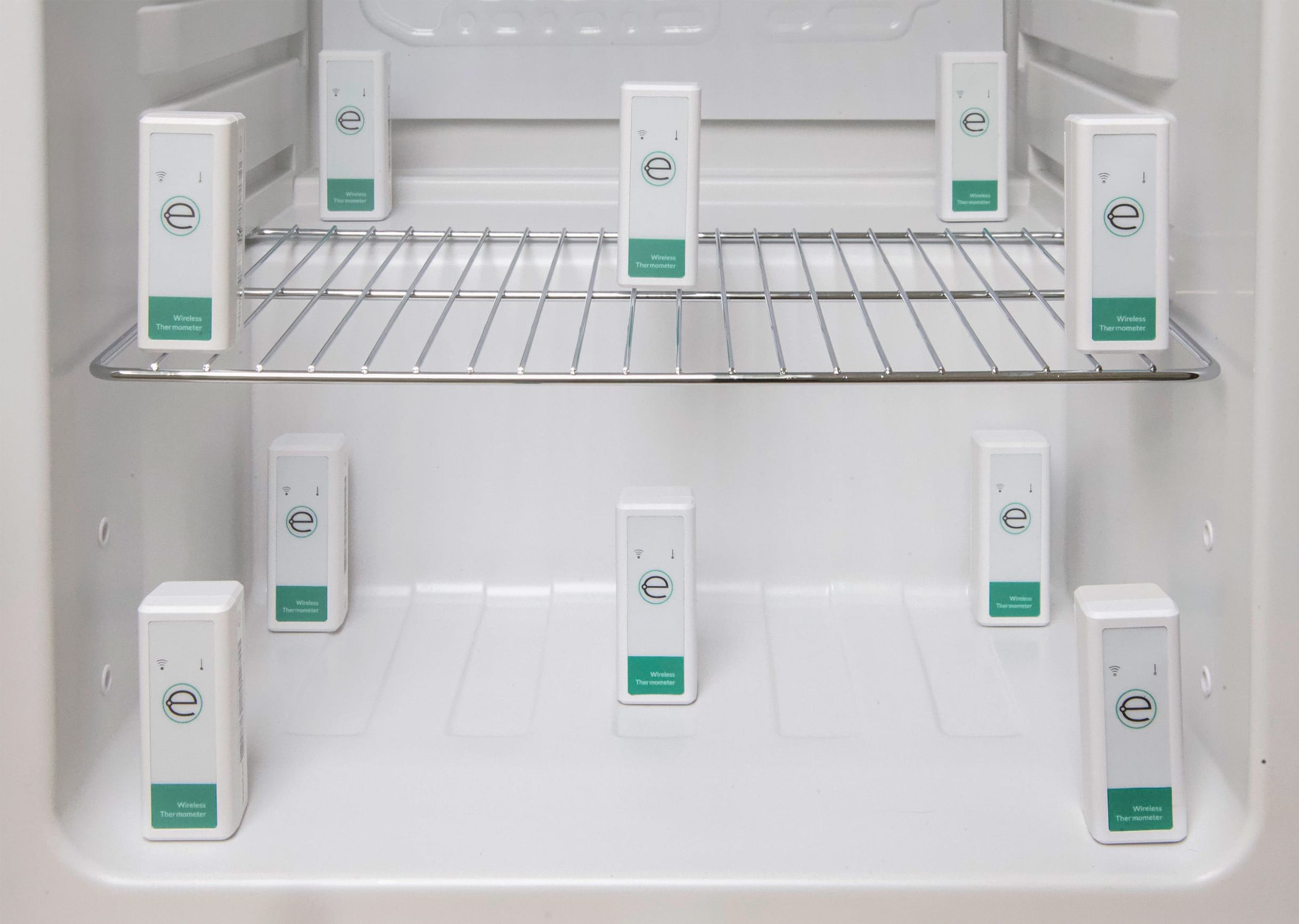 Interior of an empty refrigerator with 10 Eupry wireless thermometer sensors placed on two shelves for temperature mapping.